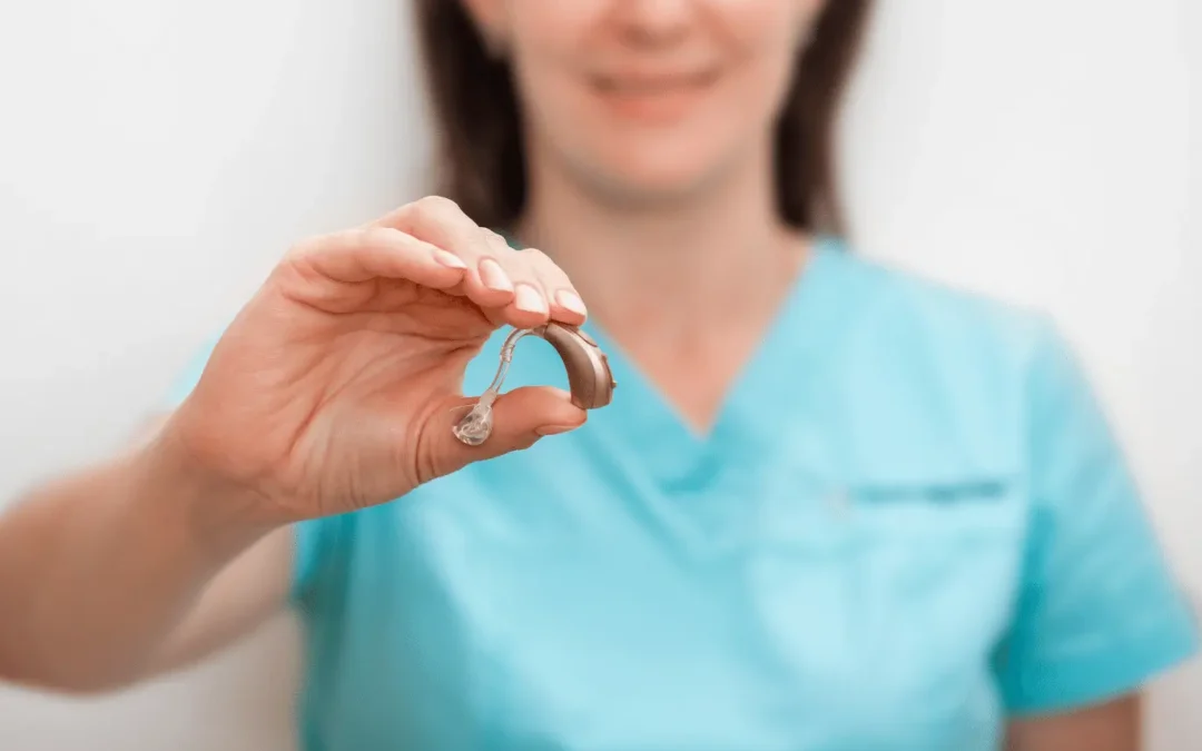 Nurse holding hearing aid for stay tuned hearing article about the benefits of hearing aid use